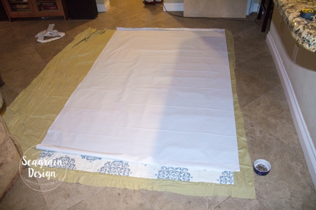 DIY No-Sew Blackout Curtain Liners by Seagrain Design | Step 1: Prep your workspace by spreading your curtain out face up on and rolling your liner fabric out face down over the curtain.